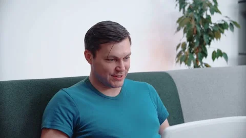 A man sits on the couch, communicates on a laptop. Close-up. Stock Footage 148570482