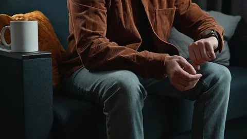 A man sits on a couch while using his hands to gesture and interact with objects Stock Footage 339097625