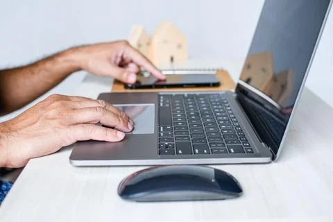 A man sits at a desk and is using a laptop computer. Stock Photos