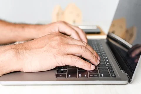 A man sits at a desk and is using a laptop computer. concept working from h.. Stock Photos