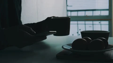A man sits at the dinner table and holds a smartphone in his hands Stock Footage 102129983