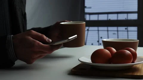 A man sits at the dinner table and holds a smartphone in his hands Stock Footage 102130035