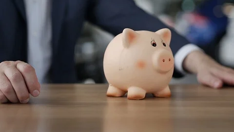 The Man Sits Down and Puts a Coin in the Piggy Bank Video stock 91737676