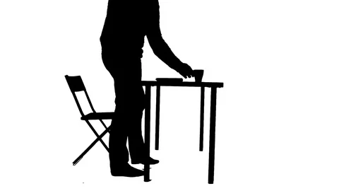 Man sits down at the table drinks coffee and uses a laptop silhouette Stock Footage 81696796