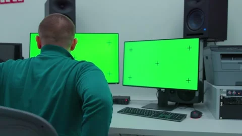 A man sits down on a working chair in the scene with two computer monitors on a Stock Footage 270397147