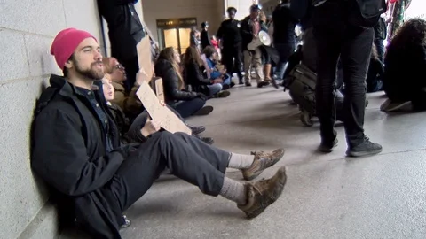 A man sits during a sit-in in front of Trump International Hotel  in Washingt Video stock 125867747