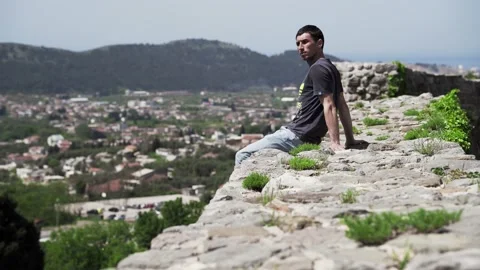 A man sits on the edge of the Old Bar fortress Stock Footage 196125947