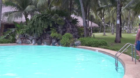 A man sits on the edge of the outdoor pool Stock Footage 91348852