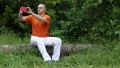Man sits on a fallen tree in the forest and makes photos on his smartphone HD Footage
