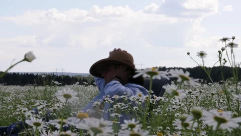 A man sits in a field of daisies and rests 스톡 동영상 278145346