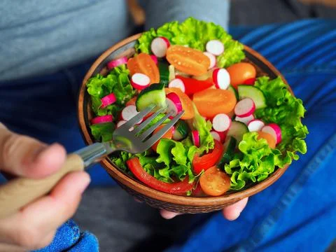 A man sits on the floor and eats a delicious green salad 스톡 사진