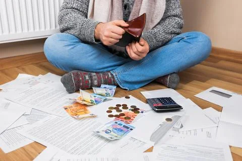 A man sits on the floor, sorting through payments, scattered bills, a calcu.. Foto stock