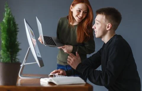 A man sits in front of a computer and tells a woman something Stock Photos