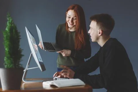 A man sits in front of a computer and tells a woman something Stock Photos