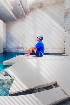 A man sits in front of a small pool and looks up Stock Photos