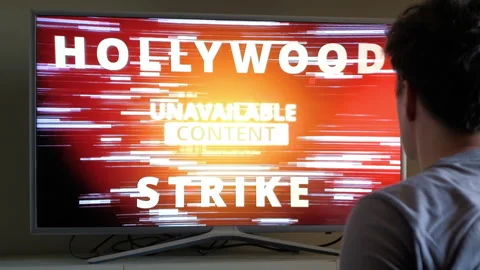 Man sits in front of TV and turns on news about Hollywood Strike 2023 Video stock 246495162