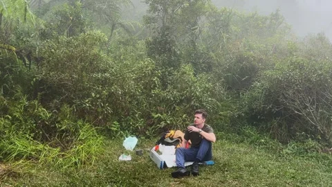 Man sits on grass and drinks freshly brewed coffee resting Stock Footage 346947231