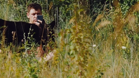 A man sits on the grass with German shepherd in the meadow and looking at the Stock Footage 111658271