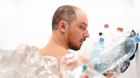 Man sits with his back in a pile of plastic Stock Footage 125329491