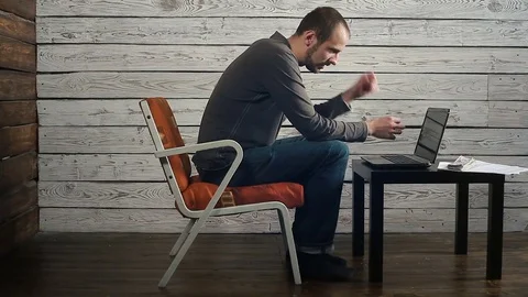 A man sits at a laptop and thinks the money Stock Footage 83473553