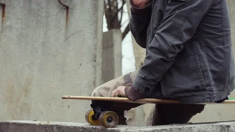 Man sits on longboard ends call and stand up. Video stock 90536752