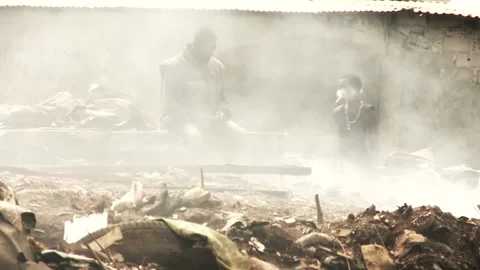 A man sits in the middle of a smoking dump. Stock Footage 218741109