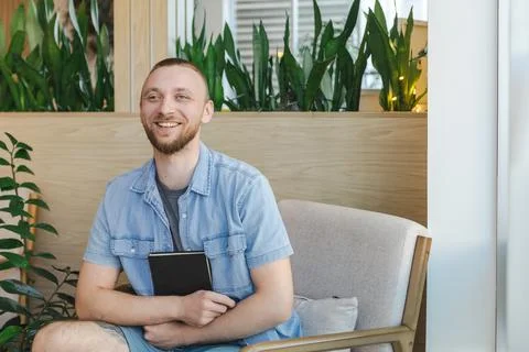 Man sits in modern space looking happy while engaging in online education o.. Stock Photos