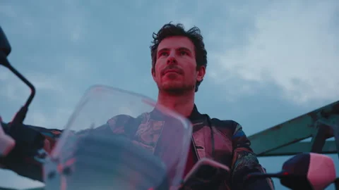A man sits on a motorcycle and looking forward. Outdoors Stock Footage 255294172