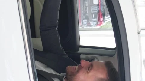 A man sits in a new electric car at a dealership and celebrates the purchase of Stock Footage 250351226