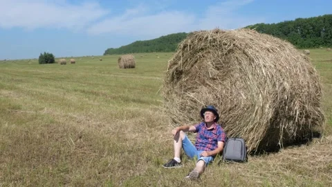 A man sits next to a haystack and enjoys nature. Stock Footage 135458081