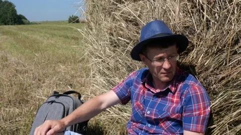 A man sits next to a haystack and enjoys nature. Stock Footage 135458122