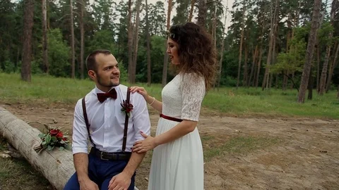 A man sits on an old fallen tree, a young woman stands beside him. Stock Footage 69885533