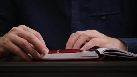 Man sits over open notebook. fingers tap on notepad thoughtfully. front view. Stock Footage 300097195