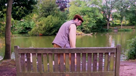 Man sits on park bench in slow motion, coming from left. Stock Footage 41760252