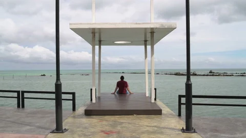 A man sits on a pier and looking at the sea Stock Footage 91789192