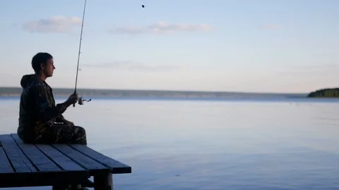 A man sits on the pier in the evening and goes fishing. HD, 1920x1080, slow Stock Footage 101502819