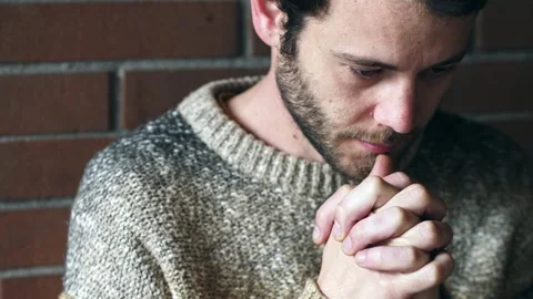 Man sits praying silently in deep personal moment Video stock 306682579
