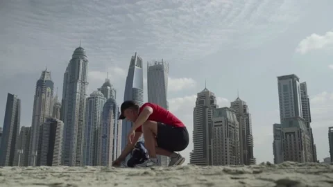 A man sits on the sand against the backdrop of Dubai skyscrapers Stock Footage 151905473
