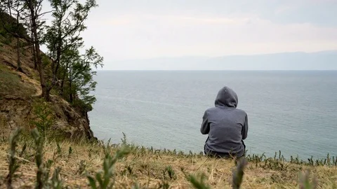 A man sits on the seashore in cloudy weather and contemplates. 4K, time lapse Video stock 79476322