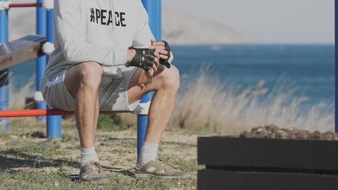 Man sits on a simulator with a bottle of water by the sea Stock Footage 129889699