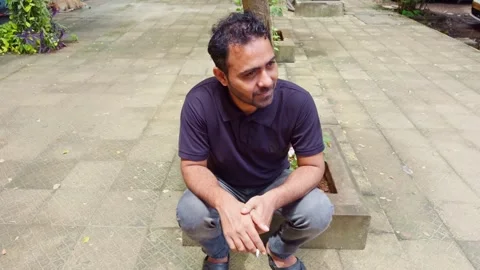 Man sits smiling and talking with cigarette in hand outdoor Stock Footage 299785215