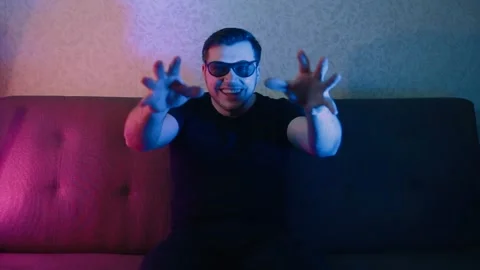 A man sits on a sofa with 3D glasses and watches an interesting scene on TV Video stock 131182309