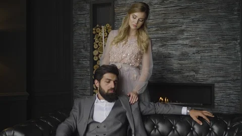 Man sits on sofa lady puts hands on shoulders from back Stock Footage 103934775
