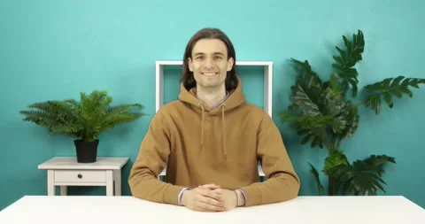Man sits at a table against a background of green plants. Stock Footage 158955261