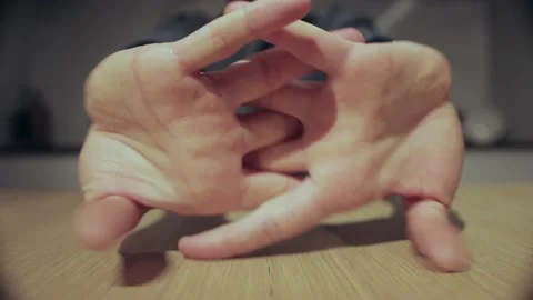 A man sits at a table and kneads his fingers and stretch oneself, close-up Stockbeeldmateriaal 166047825