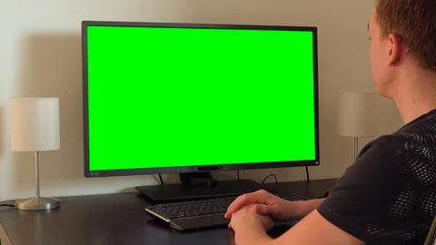 A man sits at a table and looks at a green computer screen Stock-Footage 87996334
