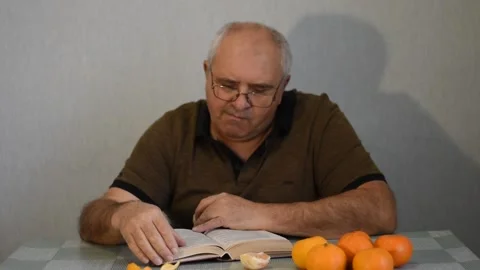 A man sits at a table and reads a book. Stock Footage 222056164