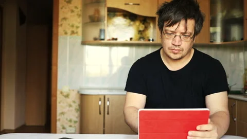 Man sits at a table and works in a tablet Stock Footage 130941600