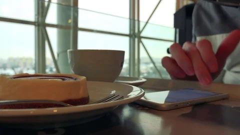 A man sits at a table with breakfast in a cafe and works on a smartphone in fast Stock Footage 77299656