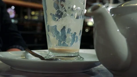 A man sits at a table in a cafe and drinks latte, is about to finish - closeup Video stock 77299388